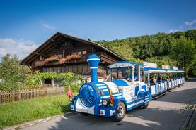 Das blau weisse Spiezer Bähndli steht vor dem traditionellen Heimat- und Rebbaumuseum